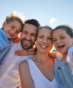 Caucasian taking a selfie on the beach. Happy family on holiday taking a photo by the ocean. Portra.