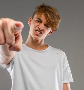 Happy caucasian male in white t-shirt gesticulating on camera isolated on grey background
